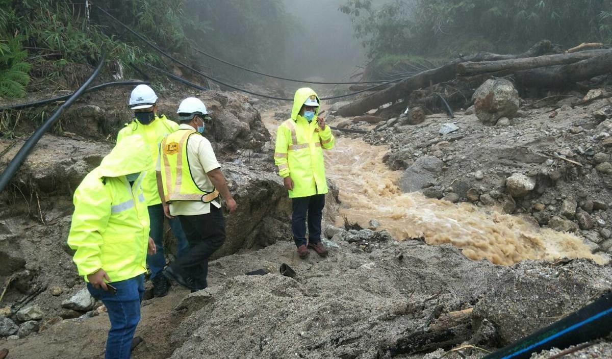 MOHAMAD Zulkefly (kanan) meneliti pengaliran air dari bukit di Lojing yang menyebabkan tanah runtuh hingga merosakkan Jalan Gua Musang-Lojing. FOTO Ramli Ibrahim