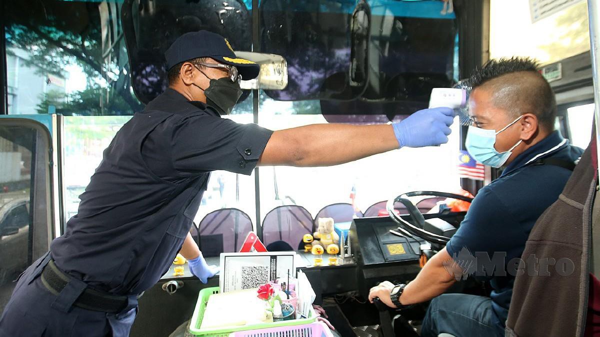 Nazli (kiri) melakukan ujian suhu terhadap pemandu bas kilang bagi memastikan mereka mematuhi SOP dalam Op Patuh di Persiaran Budiman, Seksyen 25 di Shah Alam hari ini. Foto Faiz Anuar 