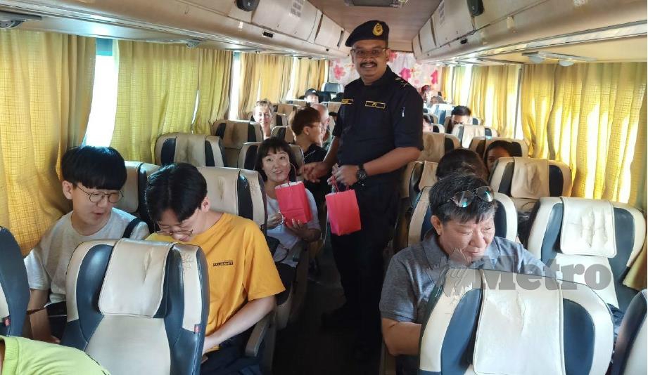 FIRDAUS beramah mesra dengan penumpang bas ekspres sempena pelancaran Ops Tahun Baru Cina di Melaka Sentral, hari ini. FOTO Nazri Abu Bakar. 