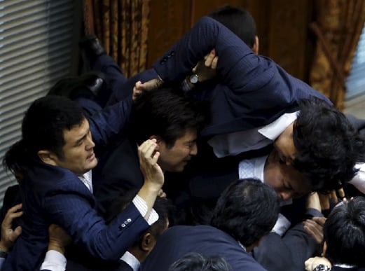 Ahli Parlimen pembangkang Hiroyuki Konishi (atas) memanjat ke atas Ahli Parlimen lain yang melindungi Speaker Yoshitada Konoike. - Foto REUTERS