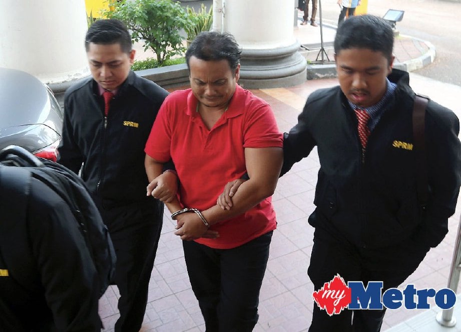 Muhammad Khudzairi diiringi pegawai SPRM ketika didakwa di Mahkamah Sesyen Johor Bahru. FOTO HAIRUL ANUAR RAHIM