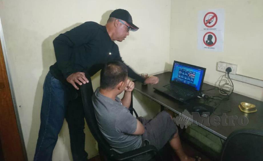 SAMSOR (kiri) memeriksa komputer riba digunakan untuk perjudian dalam talian ketika serbuan di pusat judi di Prima Seri Gombak, Gombak, malam tadi. FOTO Norizuan Shamsuddin.