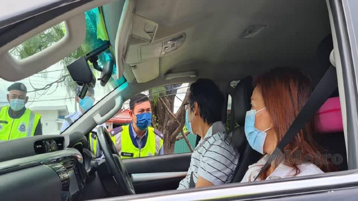 Mohd Haris melakukan pemeriksaan ke atas pemandu dalam sekatan jalan raya di Penampang. FOTO Juwan Riduan