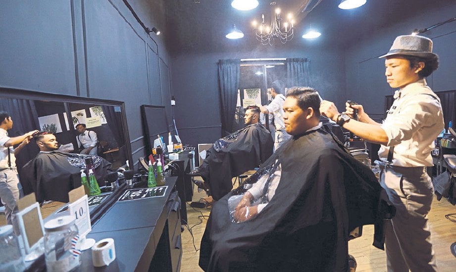 KETUA pendandan Muhammad Aliuddin Hafiz Lokman memotong rambut pelanggan.