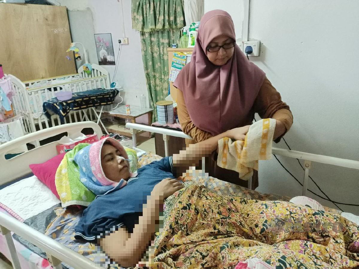 IZATUL Izriqin mengelap badan kakaknya, Hasnini Zaidura yang lumpuh dari pinggang ke bawah sejak 11 tahun lalu akibat kemalangan jalan raya. FOTO Siti Rohana Idris