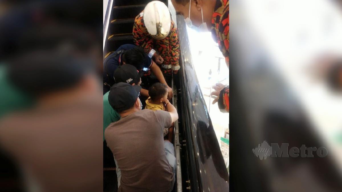 ANGGOTA bomba mengeluarkan kaki kanak-kanak yang tersepit pada eskalator di sebuah pusat beli-belah. FOTO ihsan bomba 