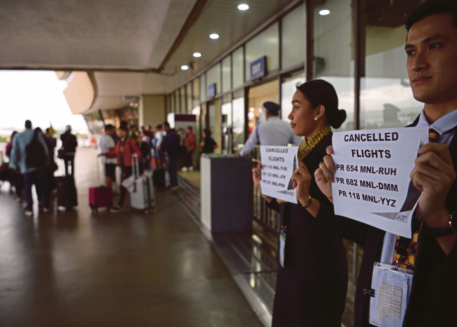 PEGAWAI syarikat penerbangan memegang kad memberitahu semua penerbangan terpaksa dibatalkan ekoran taufan Kamurri. FOTO: AFP