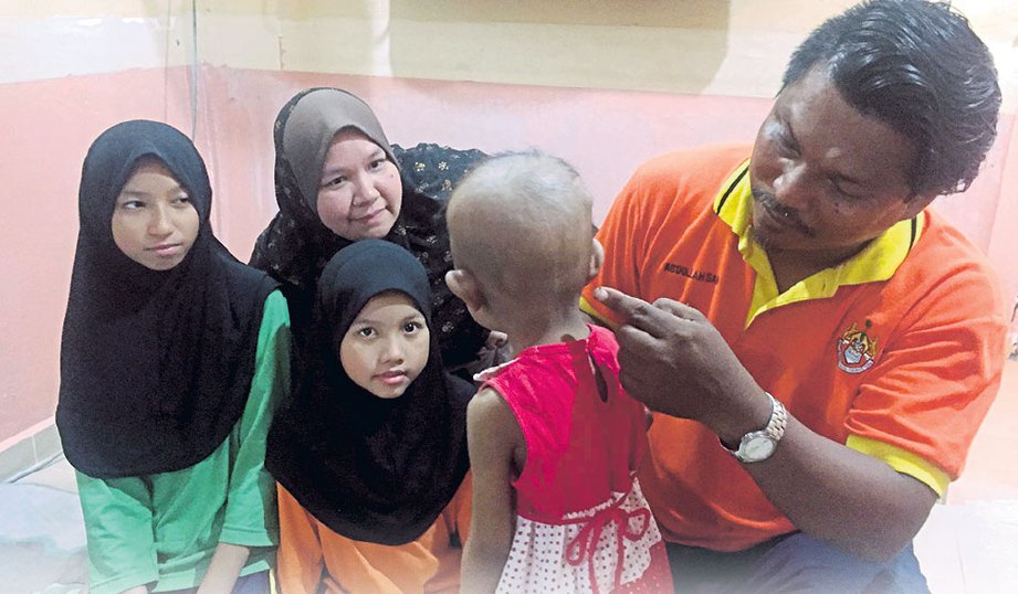 ABDULLAH Sani menunjukkan kesan pembedahan yang dilalui anak perempuannya, Nur Syafa Arianna sambil diperhatikan isterinya, Siti Khadijah Latifah Muhd Yusop. 