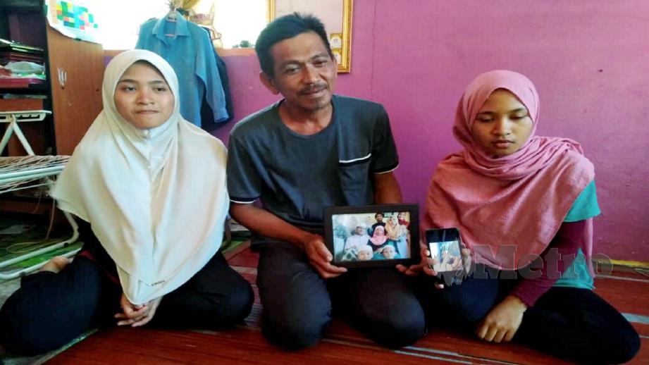 Amir Shariffuddin menunjukkan gambar keluarganya bersama Fildati Amalina sambil ditemani dua anak perempuannya di rumah mereka Kampung Baru, Sabak Bernam. Foto Amirul Aiman Hamsuddin