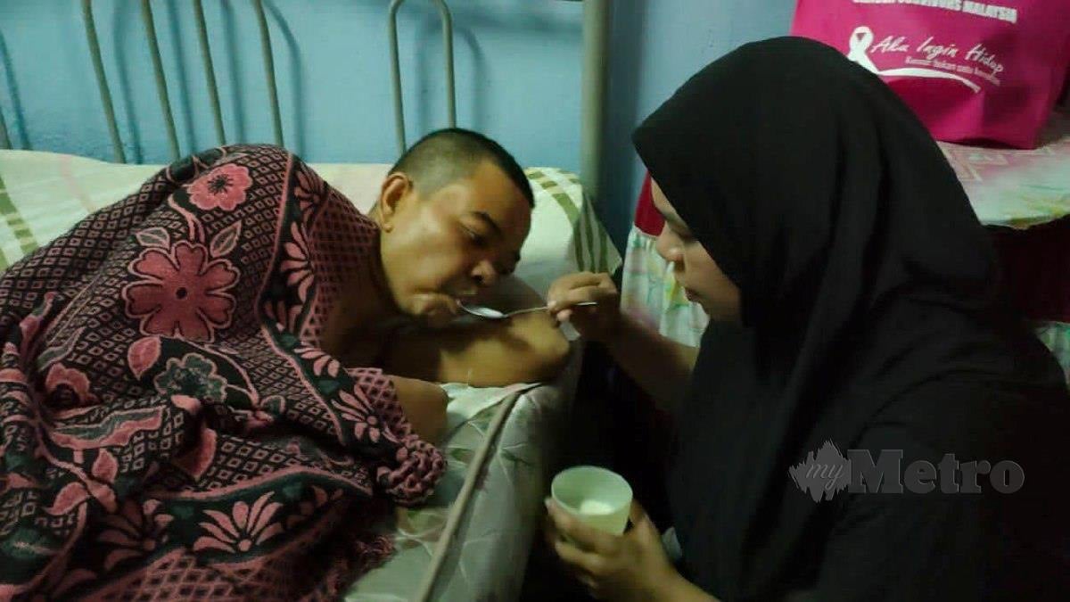Ardayani menyuap susu kepada suaminya, Muhammad Hafidz yang terlantar akibat menghidap kanser usus tahap empat. FOTO ZULIATY ZULKIFFLI