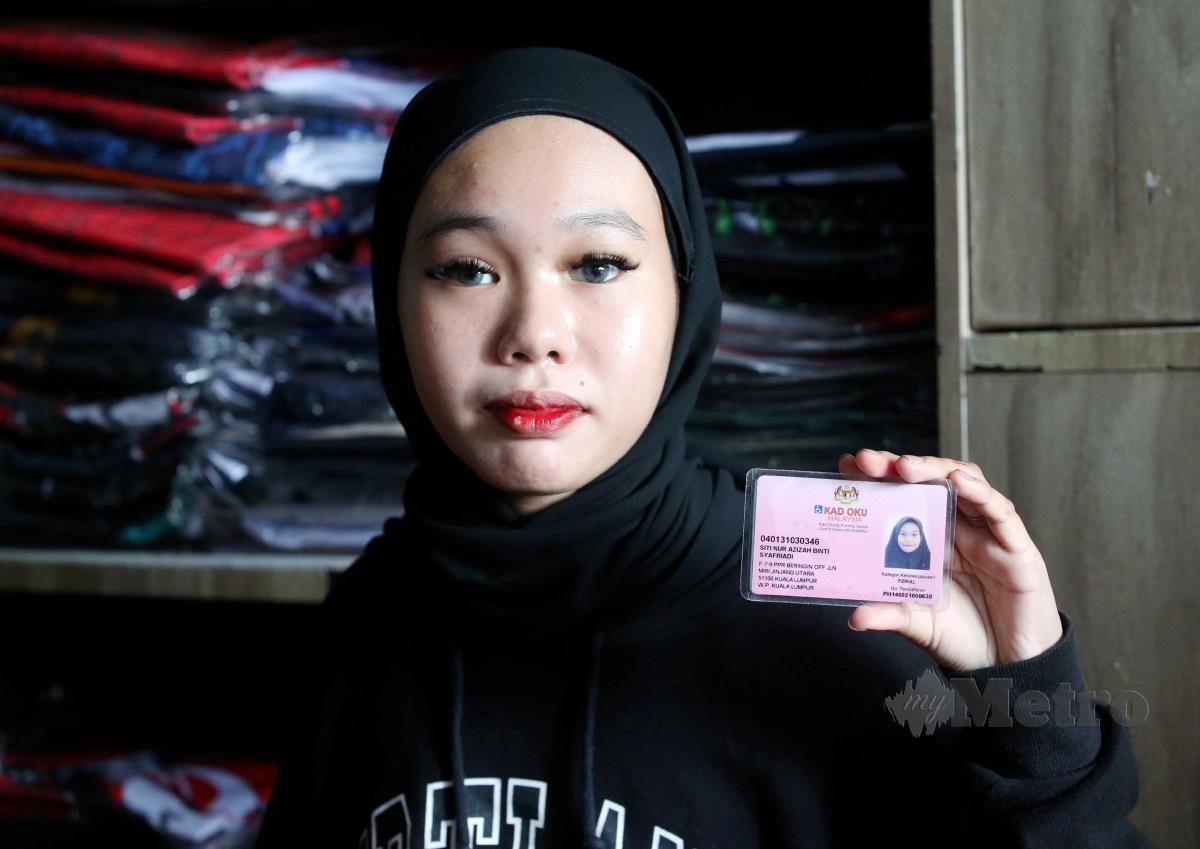 Siti Nur Azizah  menunjukkan kad OKU. FOTO EIZAIRI SHAMSUDIN