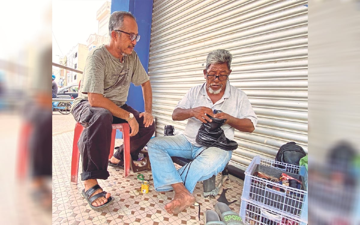 ABD Aziz  menjahit kasut pelanggan di kaki lima bandar Kuala Krai. sambil diperhatikan seorang pelanggan. FOTO HAZIRA AHMAD ZAIDI