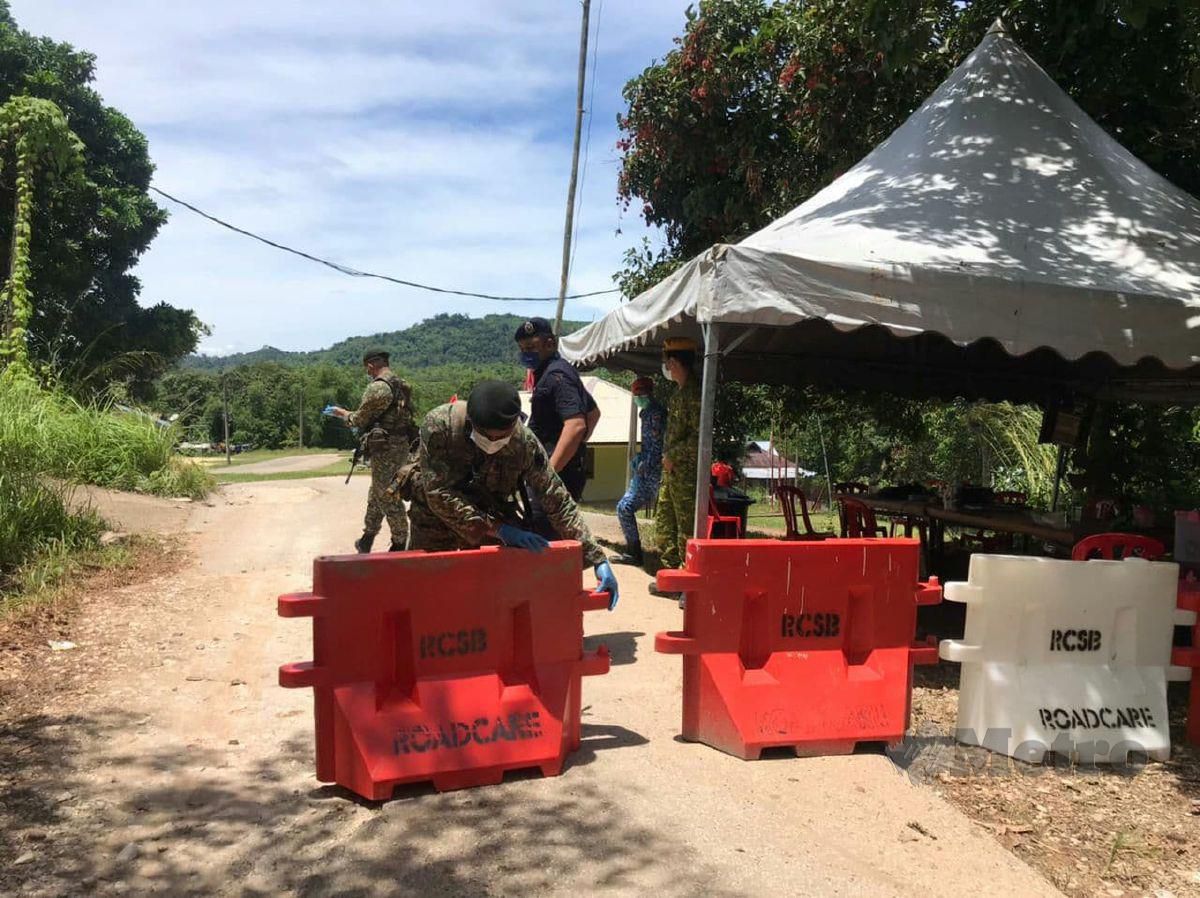 ANGGOTA pasukan keselamatan mengawal jalan masuk ke Pos Blau apabila dua kampung Orang Asli dikenakan PKPD bermula Selasa lalu. FOTO RAMLI IBRAHIM.