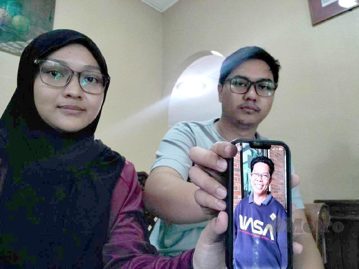 MUHAMMAD Amir Hakimi dan kakaknya, Suraiya Izzaty menunjukkan gambar bapa mereka, Sabari yang hilang sejak 3 September lalu. FOTO Noorazura Abdul Rahman