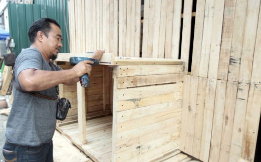 AHMAD Taufik gigih menyiapkan kaunter jurujual berasaskan kayu palet.