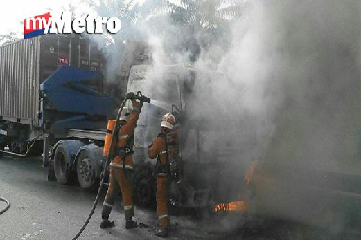 Anggota bomba bertungkus-lumus memadamkan kebakaran bahagian hadapan lori kontena berhampiran Plaza Tol Kota Kemuning, Lebuhraya KESAS, petang tadi.