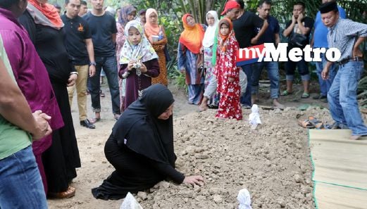Heresa di sisi kubur suaminya di Tanah Perkuburan Islam Pekan Sepang, petang tadi. FOTO Mohd Fadli Hamzah