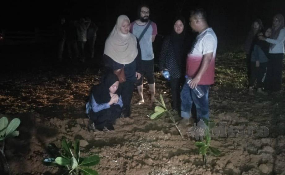 NUR Syafanis (kiri) berdoa di pusara ibu bapa dan adiknya yang dikebumikan di Tanah Perkuburan Islam Felda Chuping, Chuping, malam tadi. FOTO Dziyaul Afnan Abdul Rahman.