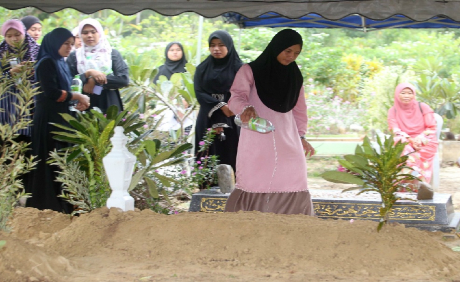 SITI Salbiah menyiram air mawar ke pusara suaminya, Mohamad Ikmal Ibrahim, 30 yang meninggal dunia akibat jangkitan virus zika di Tanah Perkuburan Islam Bukit Rangin. FOTO MUHD ASYRAF SAWAL