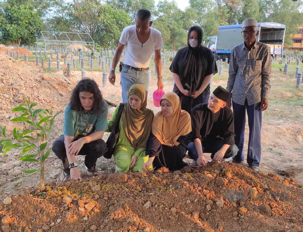 (DARI kiri) Mohd Firdaus, Siti Fairuz dan Nor Azrina di pusara ayah mereka di Tanah Perkuburan Taman Uda. FOTO IZZALI ISMAIL