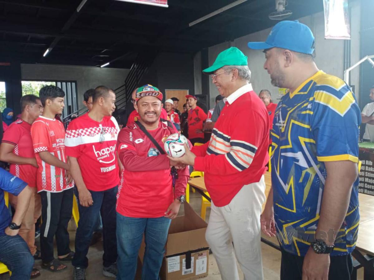 ANUAR (dua dari kanan) menyampaikan cenderahati kepada penyokong The Red Warriors (TRW) Kelantan FC yang hadir ke majlis sambutan ulangtahun TRR Treble 2012 di Kota Bharu. FOTO Nor Amalina Alias 