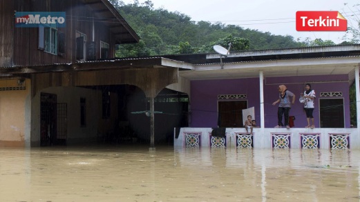 MANGSA banjir terpaksa memanjat tembok rumah akibat limpahan air sungai. FOTO Bernama