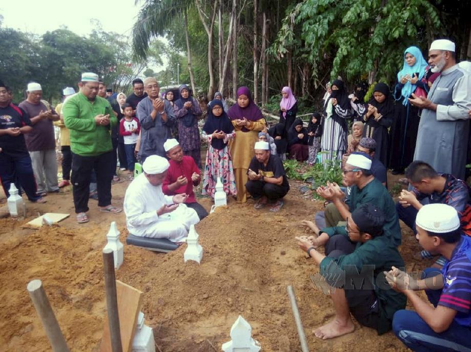 MOHD SAID duduk, tiga dari kanan) mengaminkan doa ketika pengebumian Mohd Danish Mirzan. FOTO Adnan Ibrahim