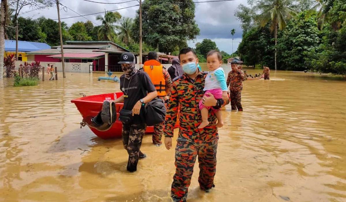 ANGGOTA bomba dan penyelamat membantu memindahkan mangsa banjir yang terkandas di Kampung Air Putih. FOTO Ihsan bomba