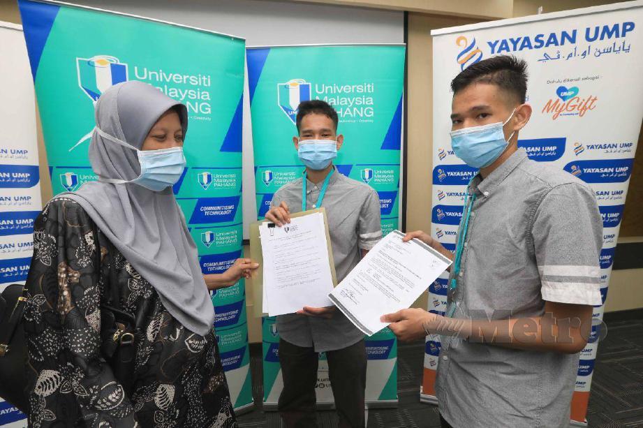 MUHAMMAD Nur Mirza (tengah) dan Muhammad Nur Izzat menunjukan surat tawaran melanjutkan ke Universiti Malaysia Pahang (UMP) kepada ibunya Sharimah Ali Man pada hari pendaftaran di UMP Gambang. FOTO MOHD RAFI MAMAT