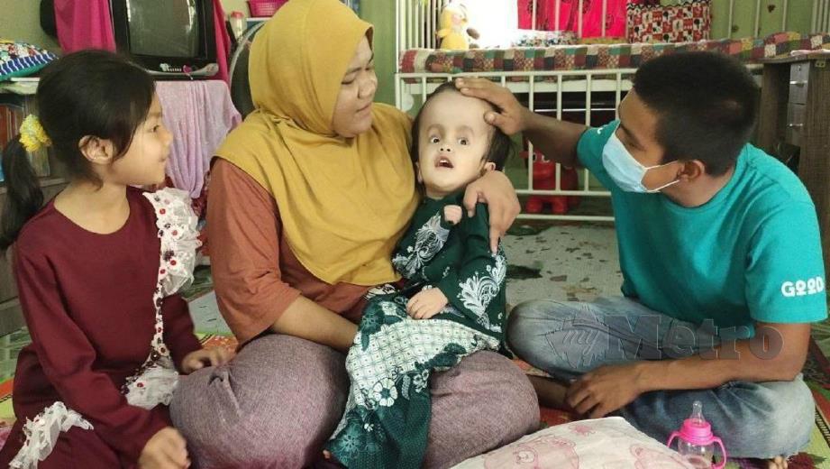 CHE Siti Nor Azreen meriba Qhayla sambil diperhatikan Mohamad Firdaus ketika ditemui di rumah mereka di Kampung Alor Stor, Alor Pasir, Tanah Merah. FOTO SYAHERAH MUSTAFA