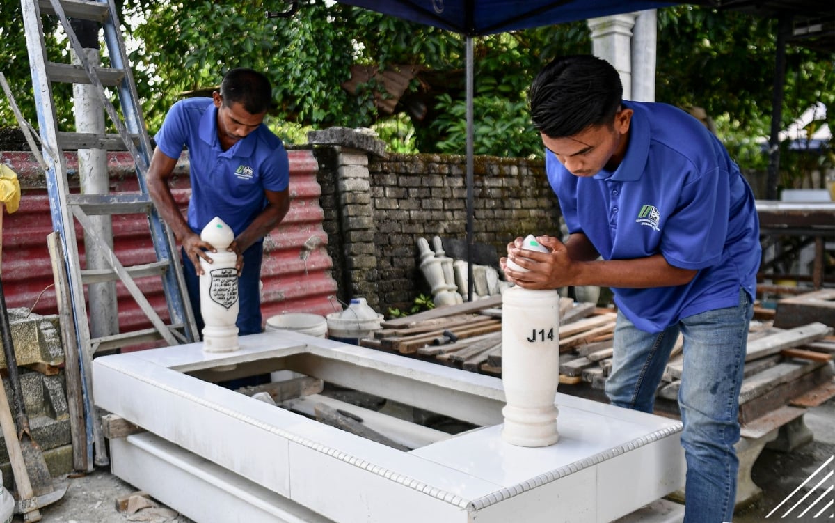 Aiman Hakim bersama abangnya Irwan Shah melakukan kerja memasang batu nisan pada kepok yang disiapkan mereka ketika ditemui di bengkel keluarga di Paya Jaras, baru-baru ini. FOTO BERNAMA