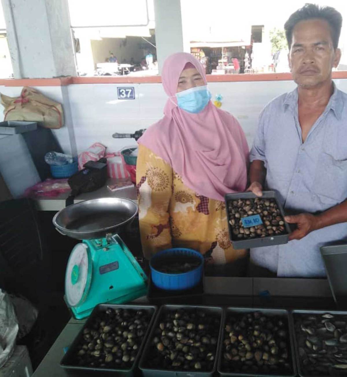 SITI Aminah dan Rusli menunjukkan kerang yang dijual pada harga RM10 sekilogram di Baazar Dorani Perdana.