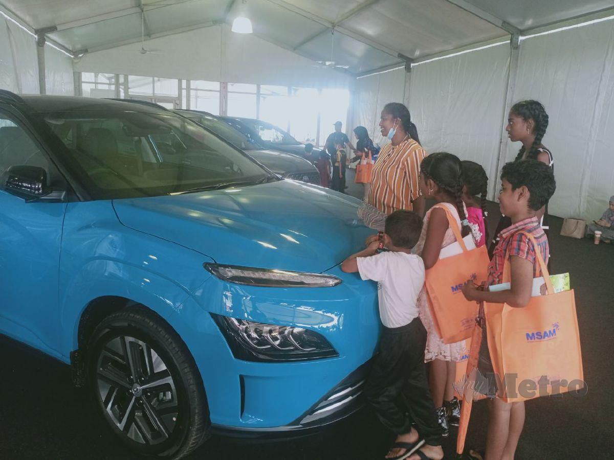 Salvemary bersama empat anaknya melihat kereta yang dipamerkan untuk Cabutan bertuah pengunjung yang datang ke tapak MSAM 2022 di Batu 1, Jalan Pantai, Port Dickson. FOTO MOHD KHIDIR ZAKARIA