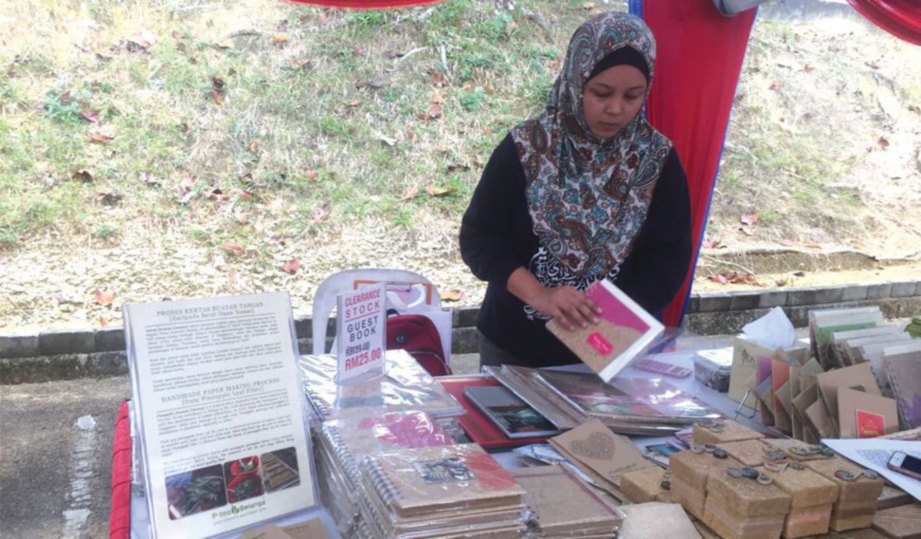 AZRA menyusun buku yang diperbuat daripada kertas nanas pada pameran Majlis Perasmian Kompleks Kraf Johor.