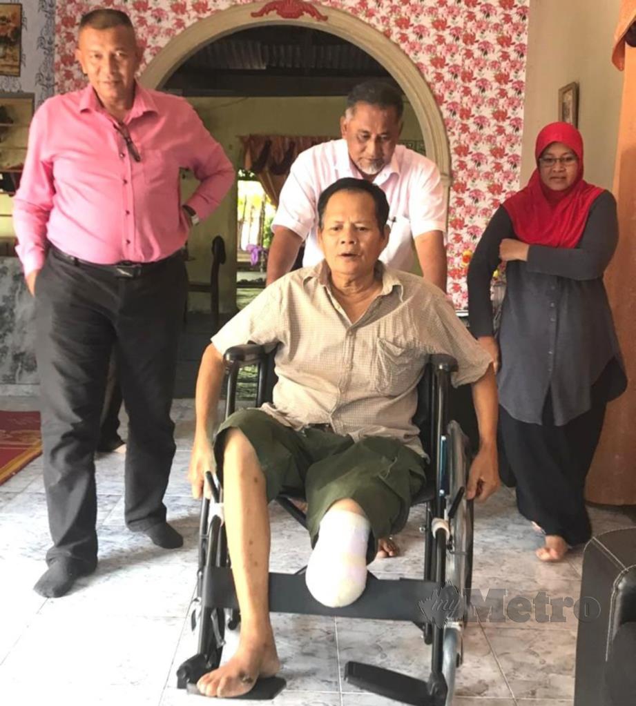 SAARI (tengah) terima bantuan kerusi roda daripada Penyelaras DUN Serting. FOTO Abnor Hamizam Abd Manap