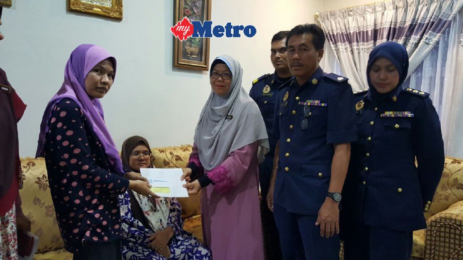 Siti Anida menerima cek Pencen Penakat daripada Pengarah Perkeso Melaka Fadhilah Hamil, di rumahnya di Taman Paya Emas, Cheng, Melaka. - Foto RASUL AZLI SAMAD
