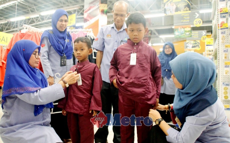 NOORHANITA (kiri) bersama pegawainya membantu memakaikan baju Melayu kepada kanak-kanak pada program pembelian kelengkapan baju raya untuk anak penerima faedah PERKESO asnaf dan fakir miskin bagi negeri Perak di Mydin Mall Meru Raya, Ipoh, hari ini. FOTO Balqis Jazimah Zahari.