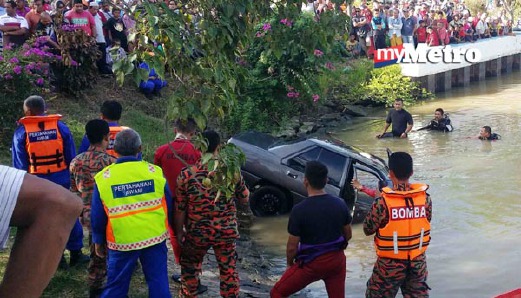 Kereta Proton Saga yang tenggelam dalam tali air di Lana Bulu tarik naik petang ini, kira-kira lapan jam selepas kenderaan itu terjunam. - Foto ZULIATY ZULKIFLI