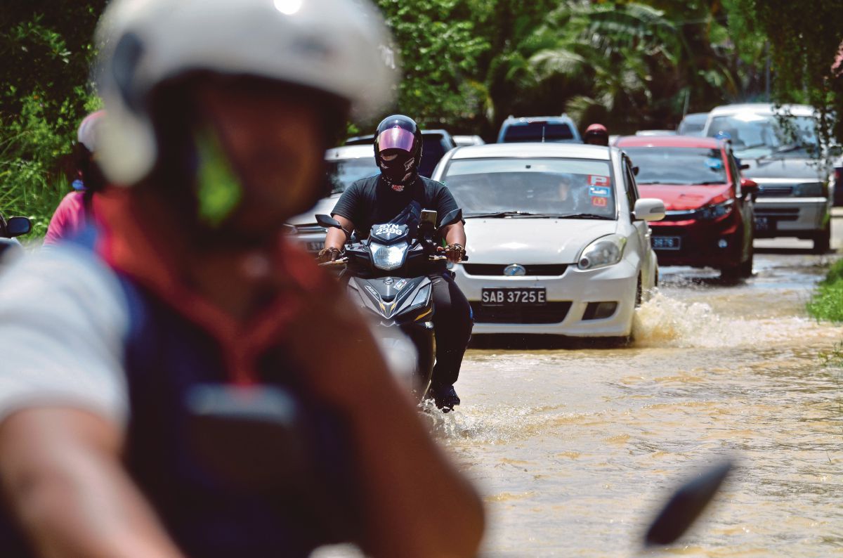 PENUNGGANG motosikal meredah banjir ketika tinjauan dibuat di Jalan Ketiau-Putatan, berhampiran Putatan, dekat Kota Kinabalu, semalam. FOTO Mohd Adam Arinin