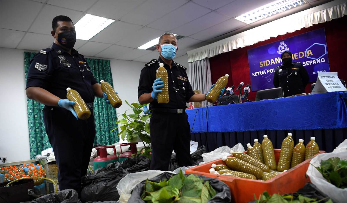 WAN Kamarul Azran (tengah) menunjukkan air ketum yang dirampas ketika sidang media di Ibu Pejabat Polis Daerah Sepang. FOTO BERNAMA