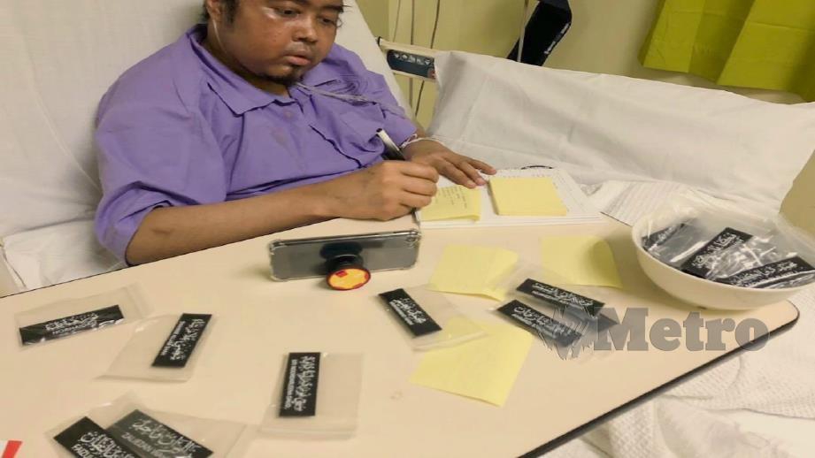 MOHD Izzuddin menghasilkan tag nama tulisan khat dari atas katil hospital.