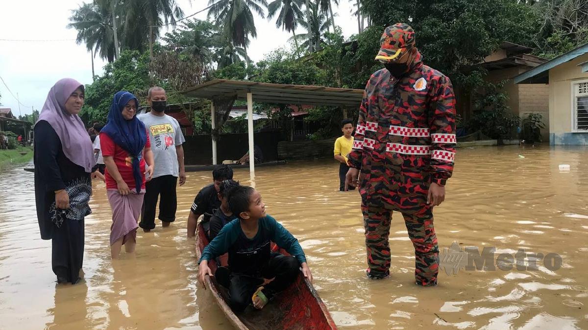 MUHAMMAD Rizwan menasihati kanak-kanak supaya jangan terlalu leka bermain banjir ketika tinjauan di Kampung Manek Urai Lama. FOTO Hazira Ahmad Zaidi