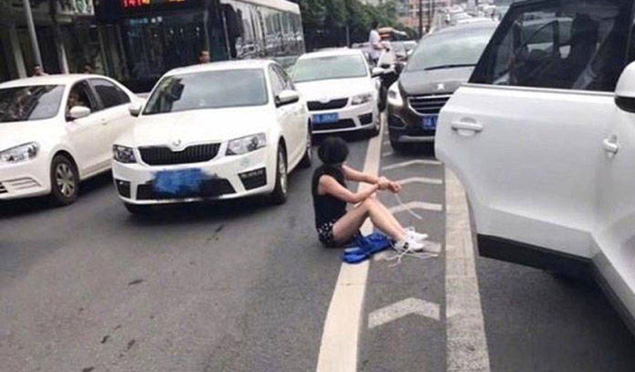 SEORANG wanita yang diculik duduk di atas jalan sambil menanggalkan tali yang diikat pada kakinya. FOTO Weibo