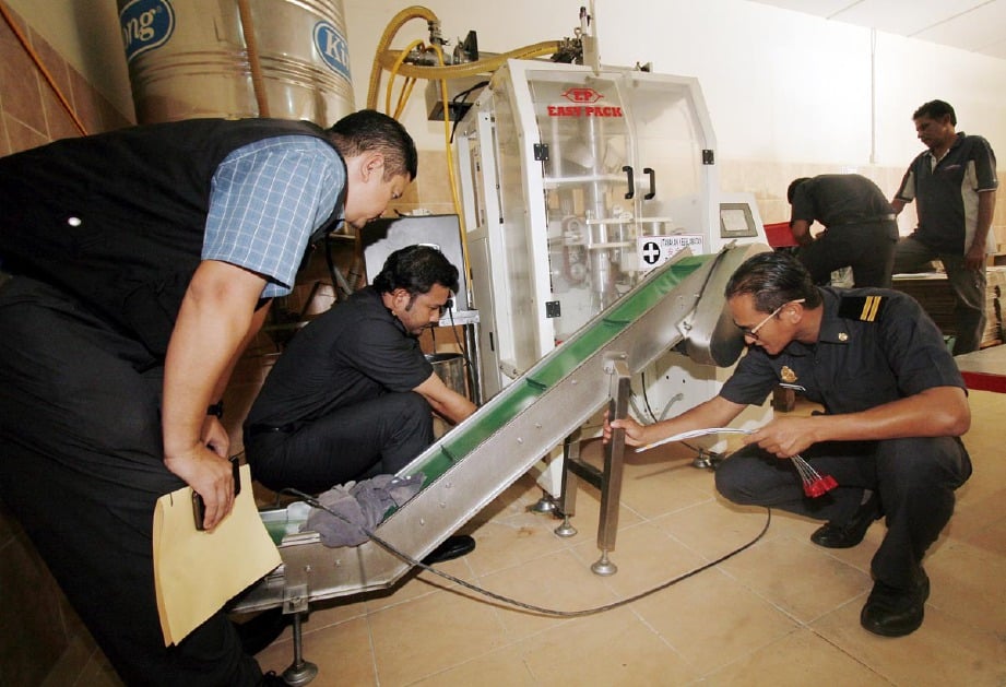 Anggota Penguatkuasa KPDNKK Pahang menyita mesin pembungkusan sebuah kilang pembungkusan semula minyak masak di Jalan Pekan-Nenasi, hari ini.  - Foto Bernama