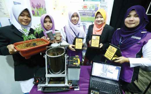 SITI Mariam (tengah), Nor Hazimah (dua dari kanan) dan Siti Norsyida bersama pelajar mereka, Nur Iman Nabilah (kiri) dan Nur Ismahani menunjukkan anugerah dan produk KITSMA.