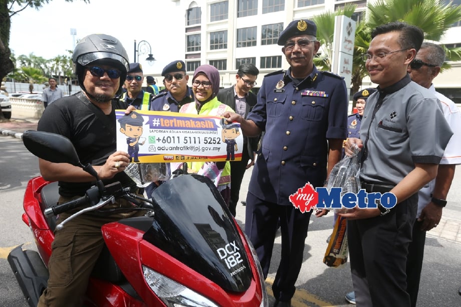 Pengarah JPJ Kelantan, Mahasan Mustapa (dua kanan) bersama Taha menyampaikan pelekat dan cenderahati kepada pengguna jalan raya. - Foto ZAMAN HURI ISA