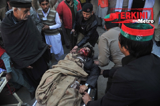 Seorang mangsa dipercaya pelajar yang cedera dikejarkan ke ambulans untuk dihantar ke hospital. - Foto AFP