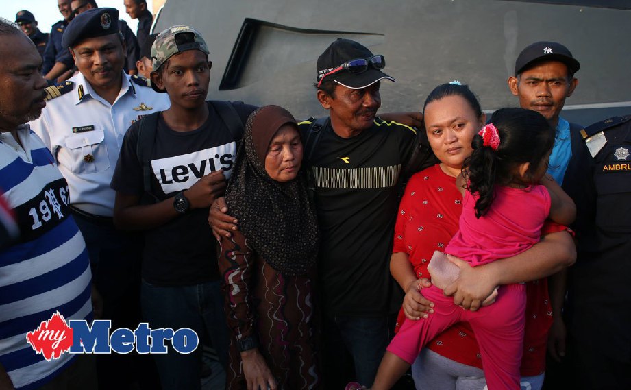 Amat (tiga kanan), dan Mohd Abdul Latiff (tiga kiri), disambut ahli keluarganya , Halimah Mohamad (tengah) ketika tiba di jeti Marina Pulau Tioman. FOTO FARIZUL HAFIZ AWANG