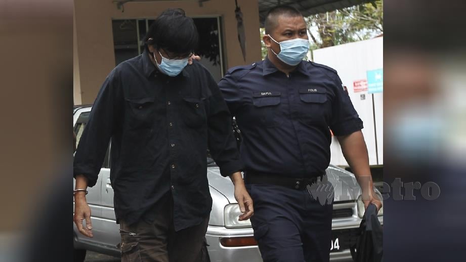 Mohd Tahir (baju hitam) diiring anggota polis ketika dibawa ke Mahkamah Sesyen Seremban hari ini. Foto Azrul Edham Mohd Aminuddin 