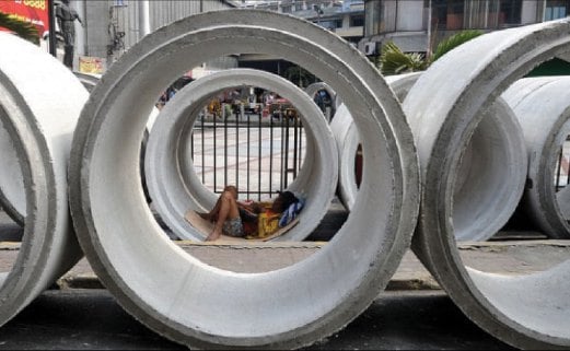 SEORANG lelaki berehat di dalam paip konkrit yang akan digunakan bagi projek sistem pengairan dan kumbahan di bandar Manila.